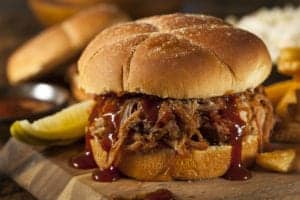pulled pork sandwich with a pickle and fries