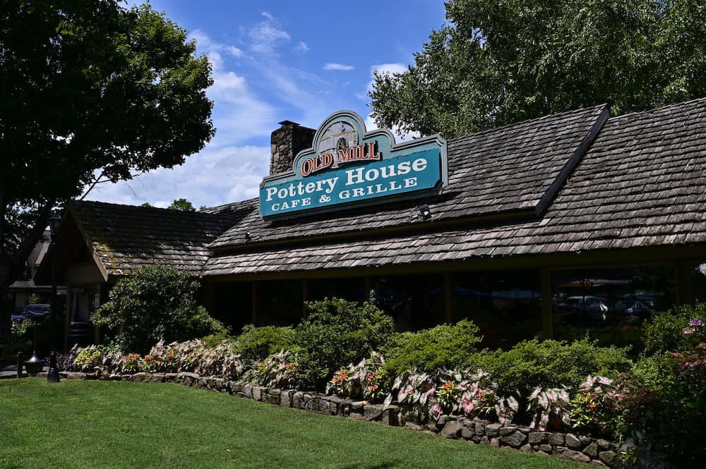 the old mill pottery house cafe building with sign and landscape in pigeon forge