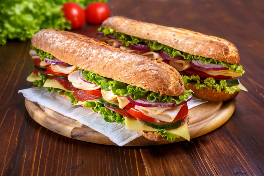 Two halves of a sandwich on a wooden plate